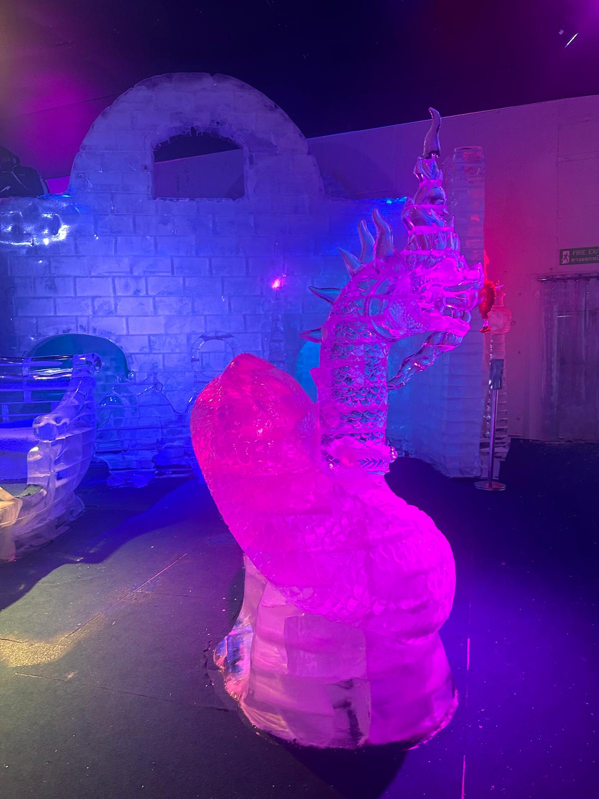 Tauchen Sie ein in eine magische Welt aus Eis und Licht, in der kunstvoll gestaltete Fabelwesen wie dieser majestätische Drache in leuchtenden Farben erstrahlen. Diese faszinierende Ausstellung verbindet meisterhafte Eiskunst mit einer stimmungsvollen Atmosphäre, die zum Staunen einlädt. Erleben Sie dieses frostige Abenteuer hautnah und lassen Sie sich von der eisigen Pracht verzaubern.